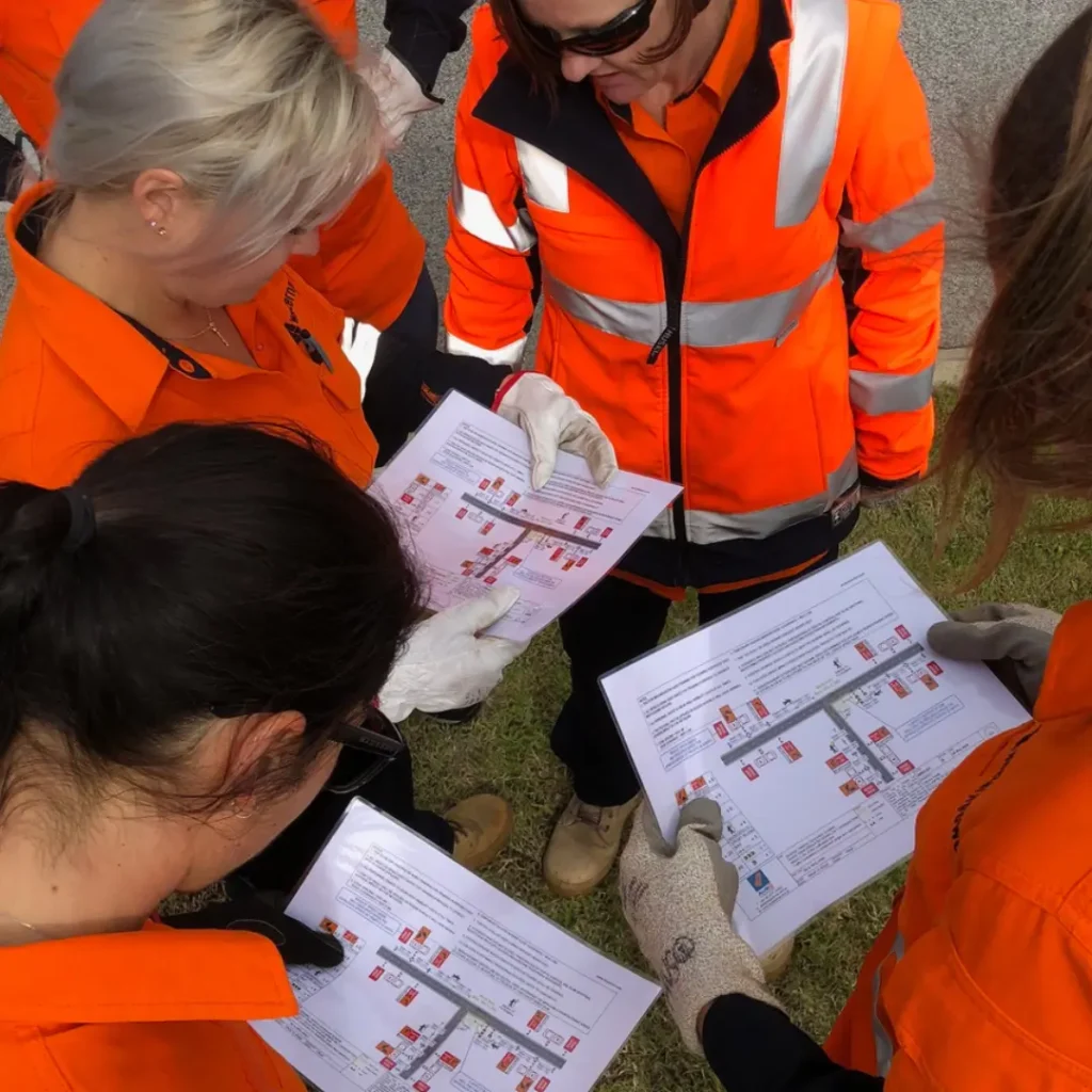 AusQ Training learners wearing high-visibility safety gear reviewing a Traffic Management Plan (TMP) during practical training session.